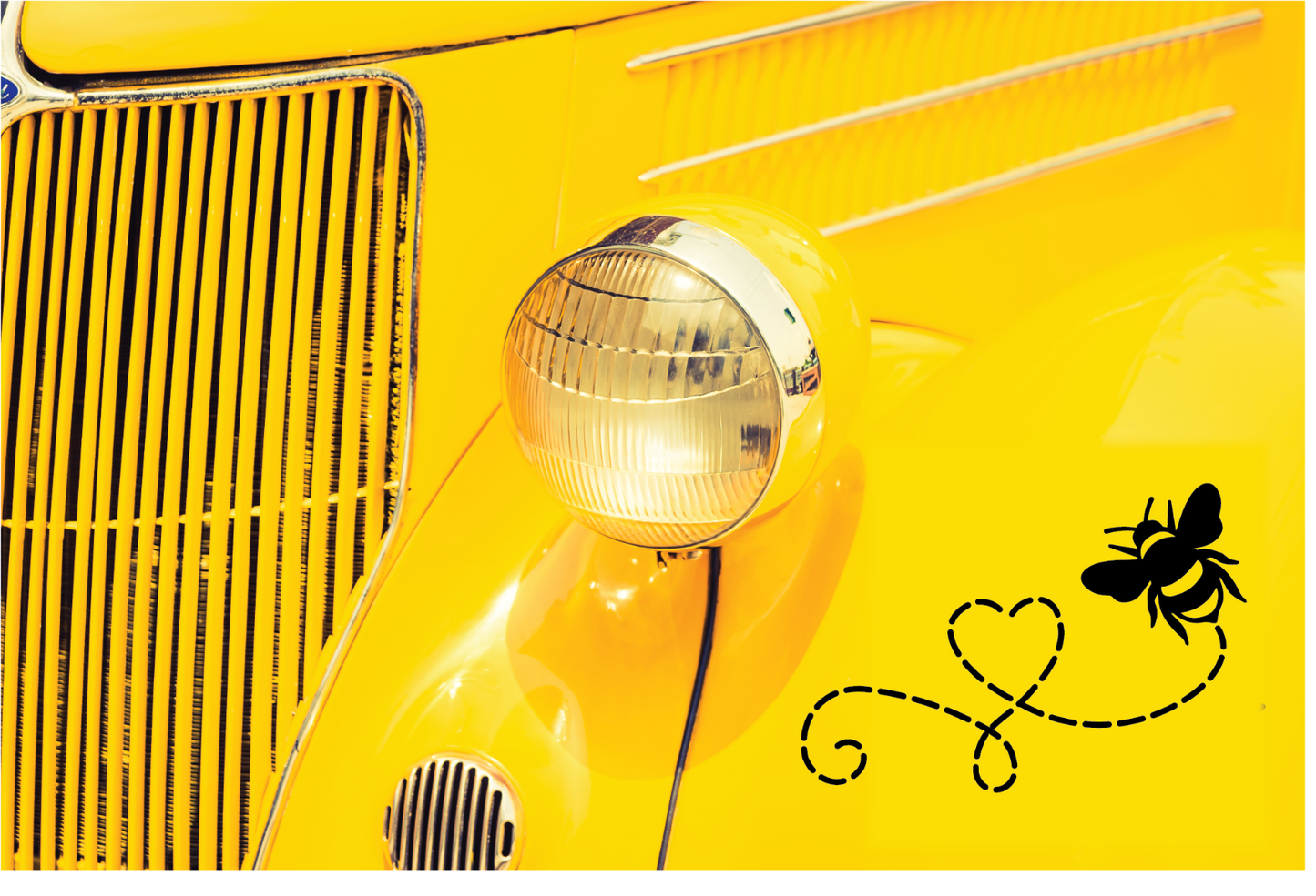 Detail view of a yellow vintage car featuring a bee decal on the chrome grille