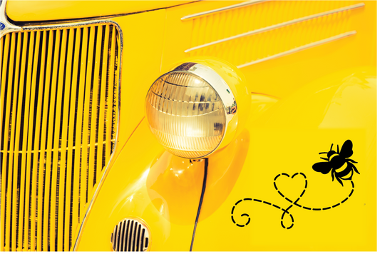 Detail view of a yellow vintage car featuring a bee decal on the chrome grille