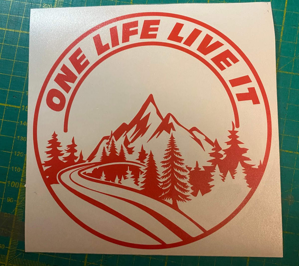 Front view of a die-cut vinyl decal sticker with a mountain graphic in red and white.